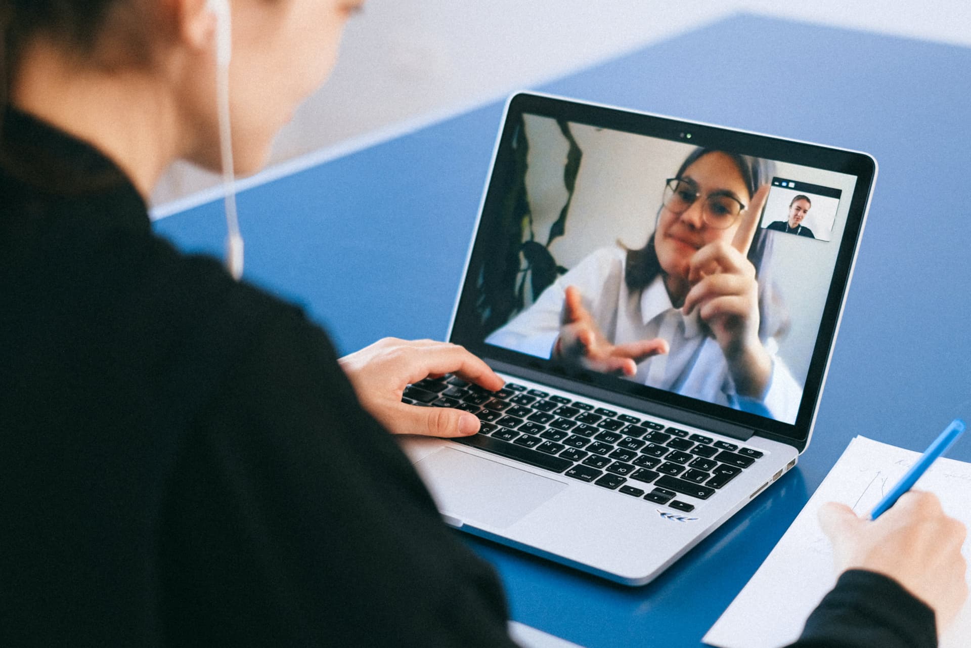 Medic on a video call on laptop while taking notes