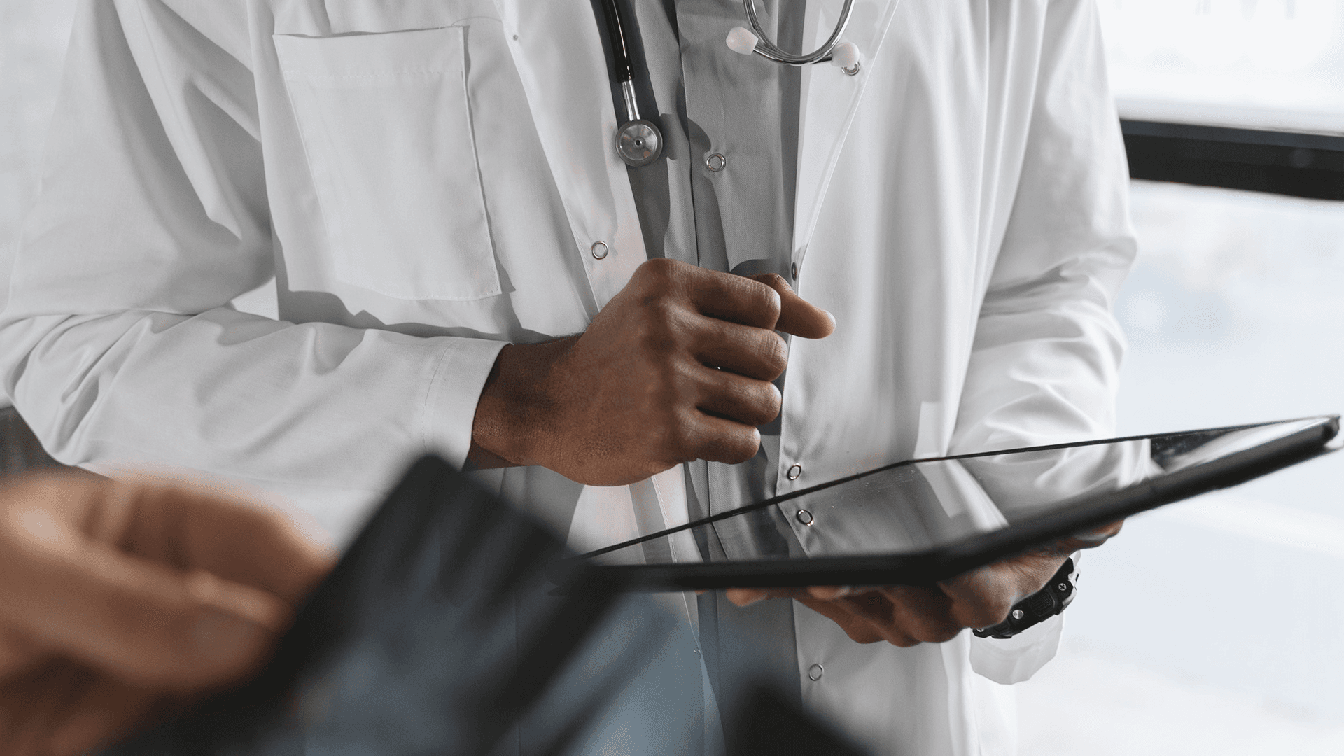 Close up of physician doctor wearing a white coat and holding a tablet