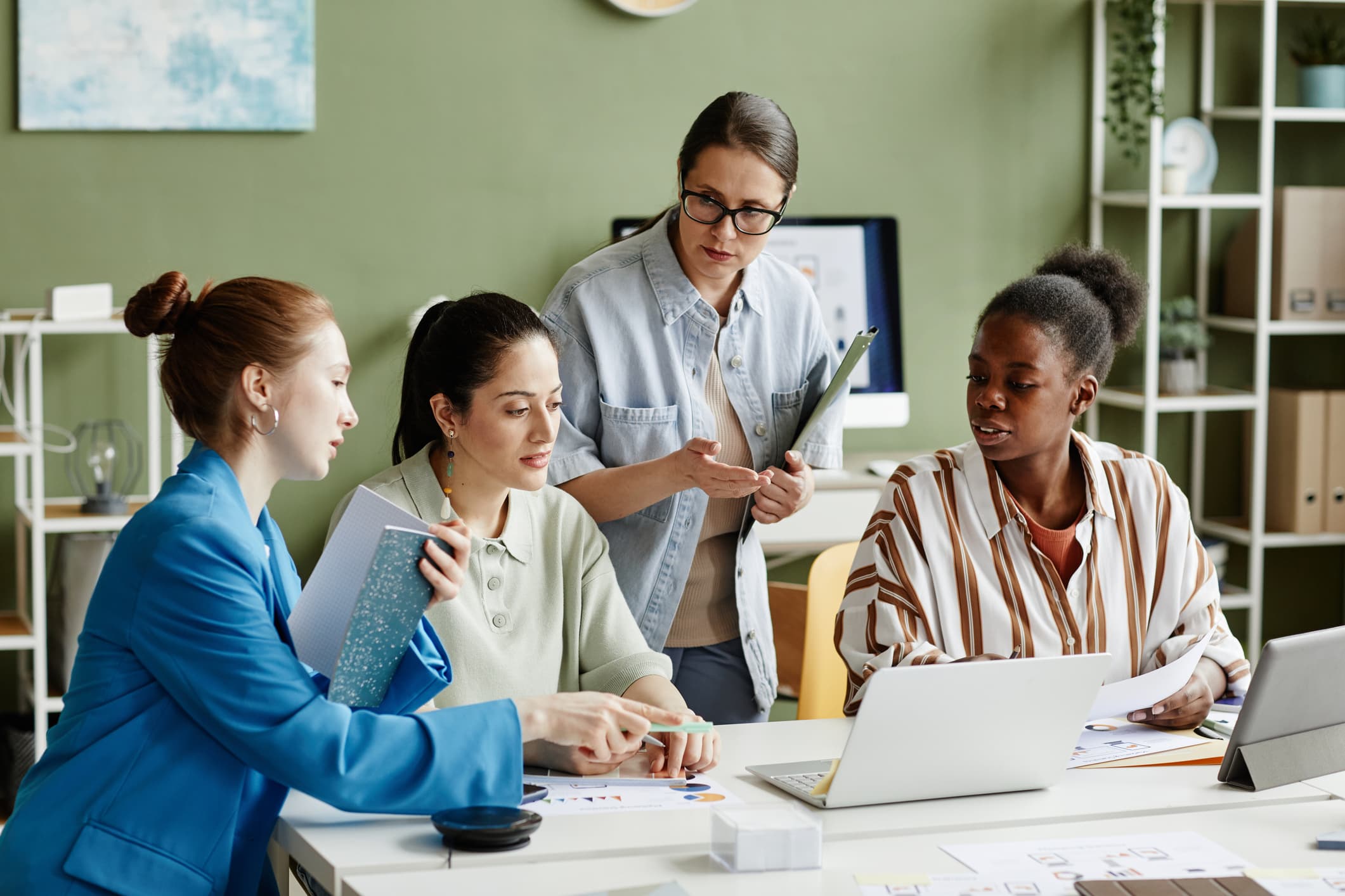 Four women gather around a laptop
