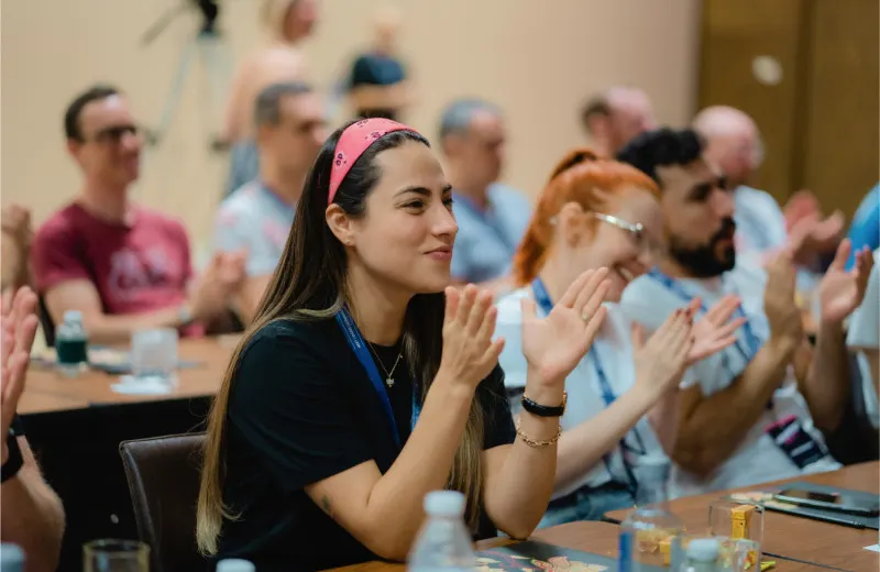 Engineer at conference sitting with peers and clapping