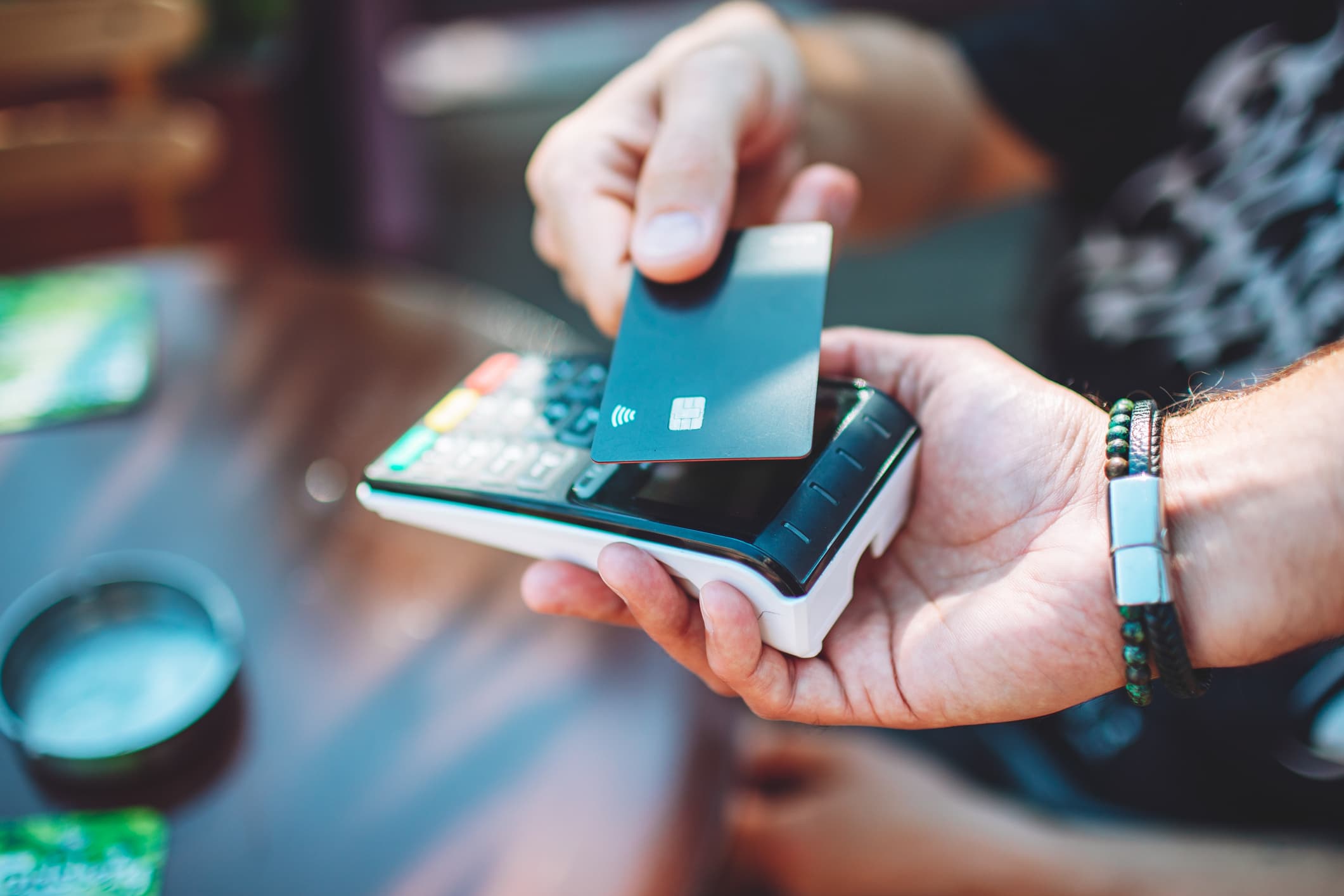 A person holds a credit card over a point of sale device