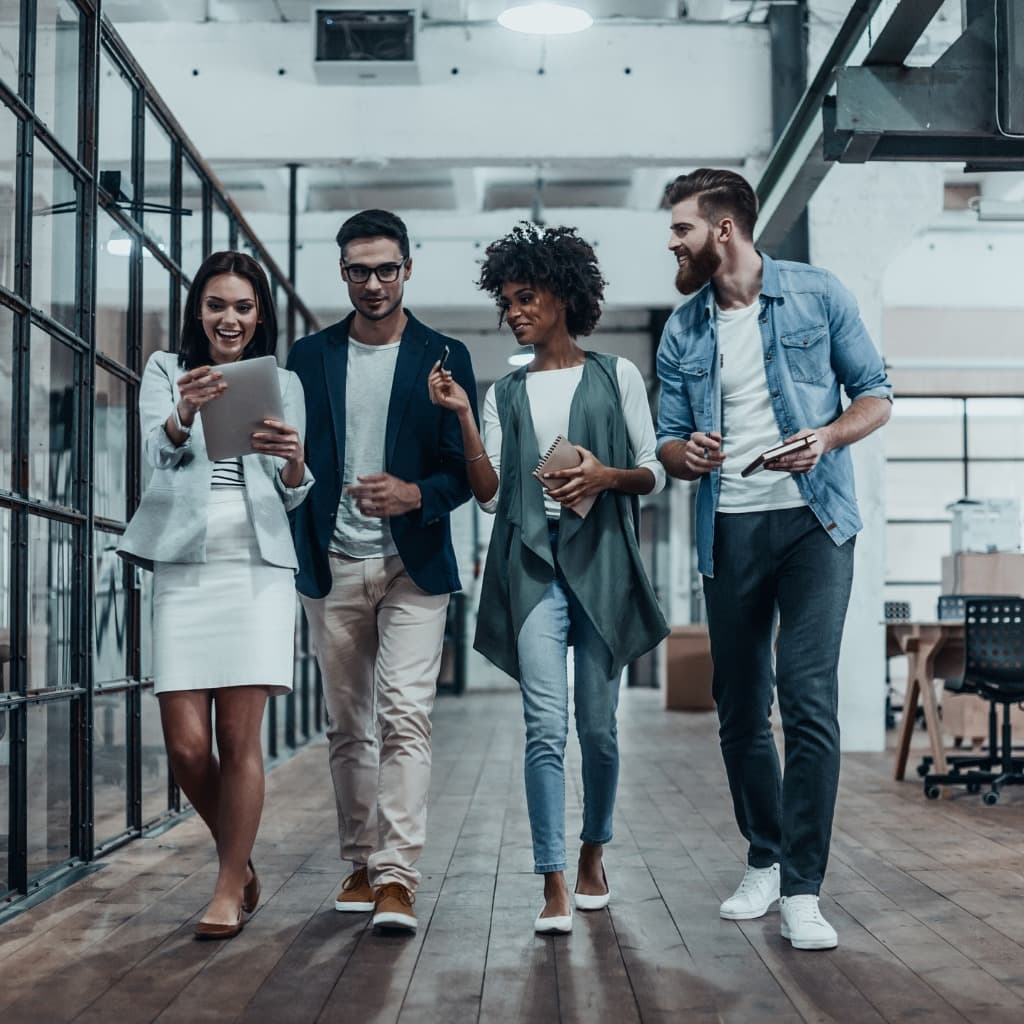 Four people walk down an office hallway
