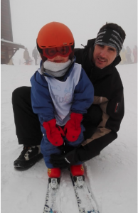 a picture of Damien Feugas, Delivery Architect, sitting in the snow with his child