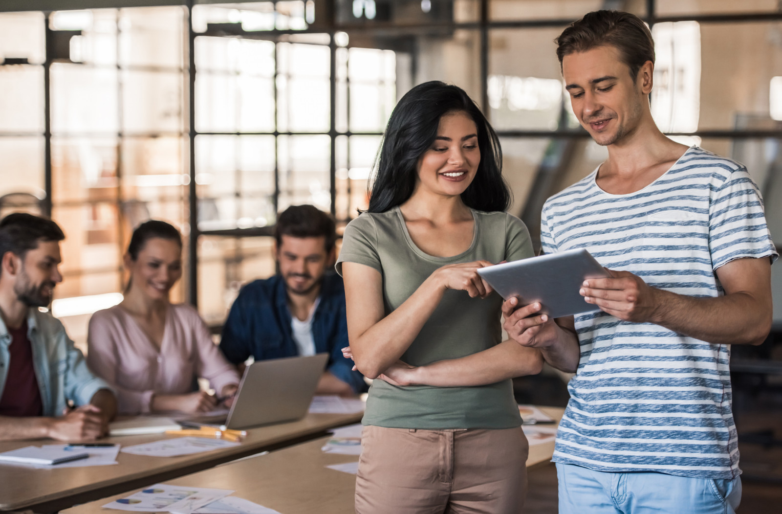 A man holds a digital tablet and shows it to a woman