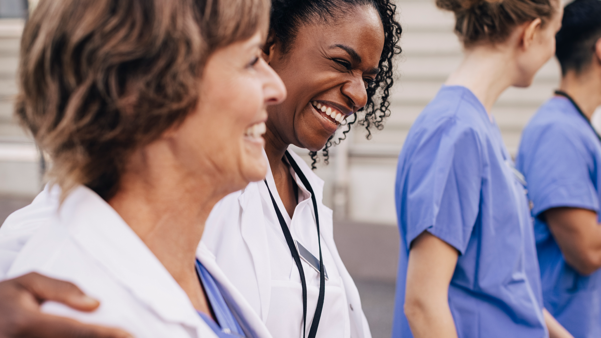 Renalytix - Happy female physician with arm around colleague outside hospital